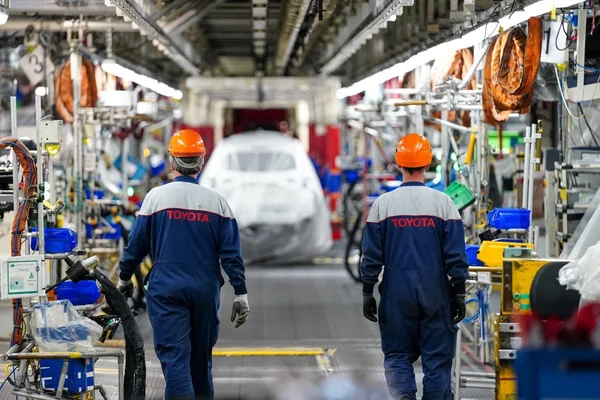 Des employés Toyota sur une ligne de montage automobile industrielle.
