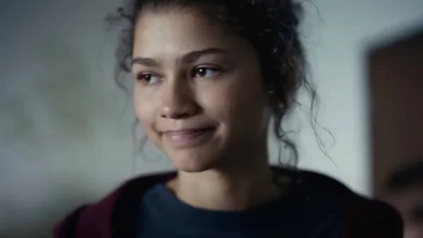 Zendaya affichant un léger sourire, portant une chemise bleue et un haut marron.