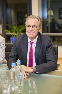Renaud Muselier en costume sombre et cravate magenta dans un bureau.