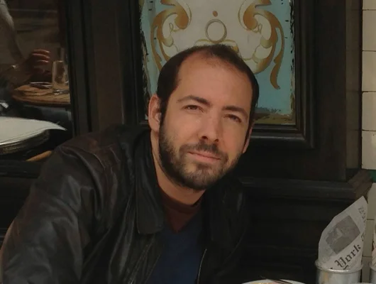 Portrait de Romain Tranchart, membre du duo Modjo, en veste de cuir assis dans un restaurant.