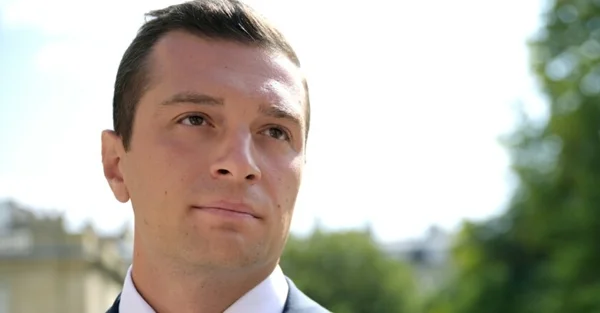 Gros plan de Jordan Bardella en extérieur.