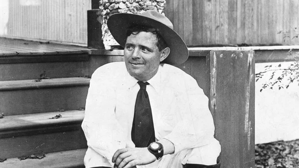 Un homme en chapeau et chemise blanche assis sur des marches en bois.