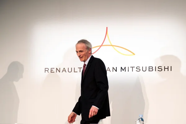 Jean-Dominique Senard marchant devant le logo de l'alliance Renault-Nissan-Mitsubishi.