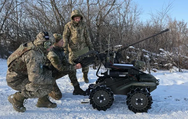Soldats ukrainiens déployant un véhicule terrestre télécommandé armé dans un environnement hivernal.