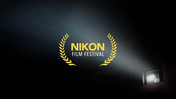 Le logo du Nikon Film Festival mis en lumière par un projecteur lors d'une projection.