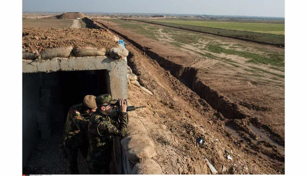 Des membres du groupe Ashab al-Kahf portant des bérets rouges et des écharpes jaunes défilant en portant des drapeaux.