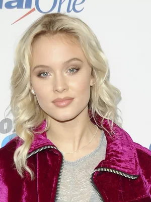 Portrait rapproché de Zara Larsson portant une veste en velours magenta.