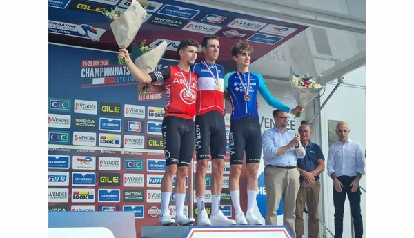 Paul Seixas sur le podium des championnats de France de cyclisme 2025, avec son bouquet et sa médaille.