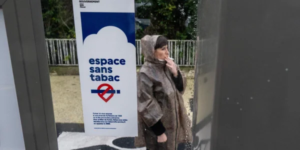 Fumeur devant un panneau indiquant un espace sans tabac.