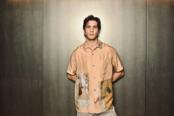 Ulysse Josselin en chemise colorée posant devant un mur métallique.