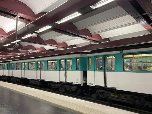 Rame  l'arrt sous les poutres rouges de la station avec des passagers aux fentres.
