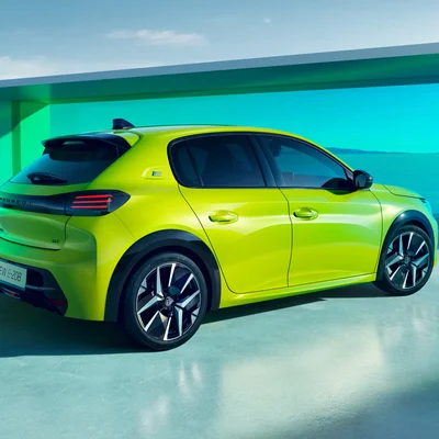 Une Peugeot e-208 GT électrique vert citron exposée dans un décor moderne aux tons turquoise.