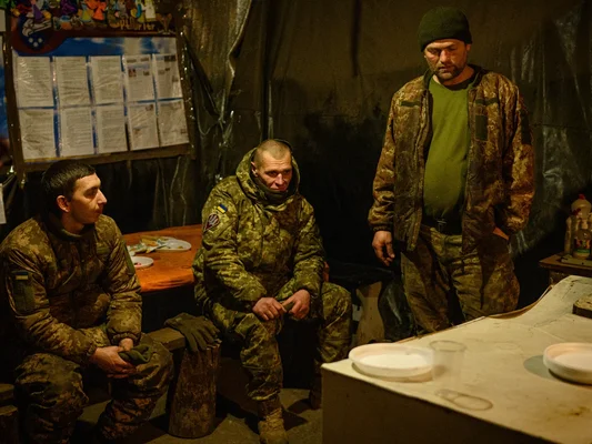 Trois soldats ukrainiens dans un abri sombre et improvisé près de la ligne de front.