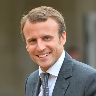 Gros plan du président Emmanuel Macron souriant en costume gris.