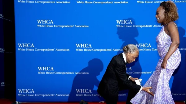 Invités arrivant au dîner des correspondants de la Maison-Blanche devant le mur des logos WHCA.