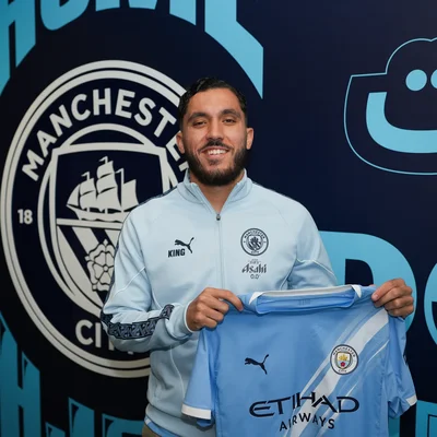 Rayan Cherki présenté officiellement tenant son nouveau maillot Manchester City.