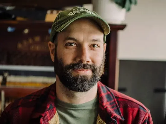 Le PDG de Patreon en casquette verte et chemise à carreaux posant pour une photographie.