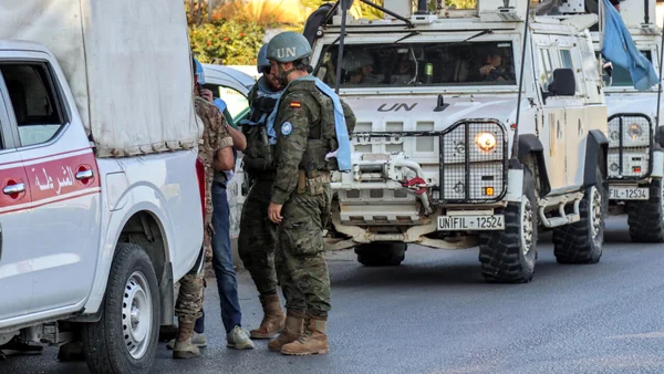 Des soldats de la paix de l'ONU se tiennent près de leurs véhicules tactiques.