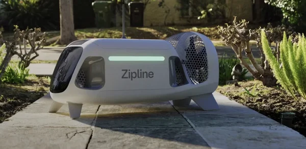 Un drone Zipline larguant un paquet parachute au-dessus du ciel bleu.