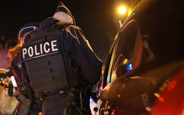 Des policiers en intervention nocturne aux côtés de leur véhicule.