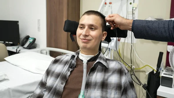 Un patient dans un lit d'hôpital avec un dispositif médical sur la tête.