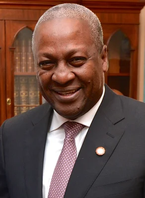 John Dramani Mahama posant devant une bibliothèque en bois.