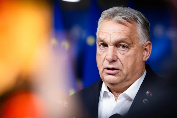 Viktor Orban en costume et chemise blanche avec une épingle au drapeau hongrois.