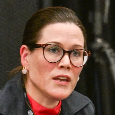Susan Coyle portant lunettes et veste sombre lors d'un événement.