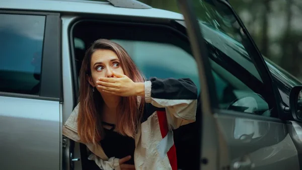 Une femme dans un SUV semblant souffrir du mal des transports, la main devant la bouche.