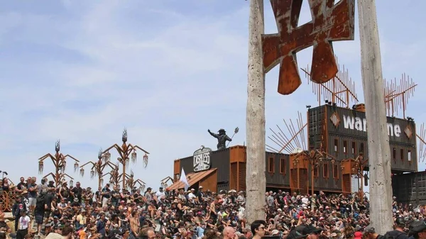 Deux riverains appuyés sur une barrière métallique près du site du Hellfest, avec des échafaudages en arrière-plan.
