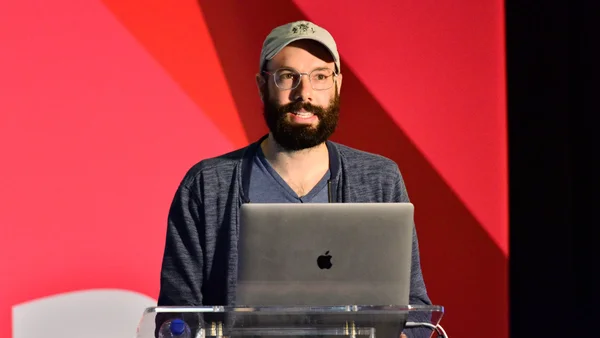 Jack Conte, PDG de Patreon, posant devant un fond géométrique rouge derrière un pupitre.
