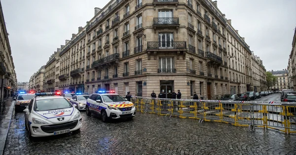 Policiers équipés derrière le ruban de scellisation près d'une entrée.
