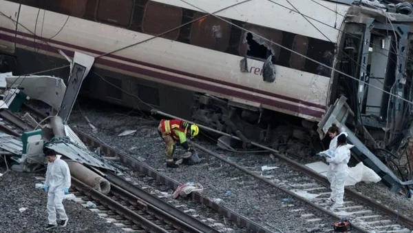 Des enquêteurs en combinaison blanche inspectent le train déraillé et ses débris.