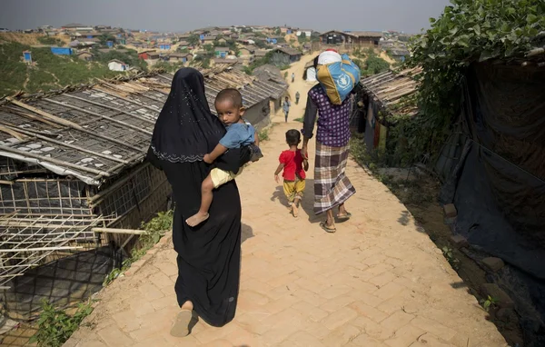 Une femme et des enfants traversant un camp de réfugiés Rohingyas au Bangladesh.