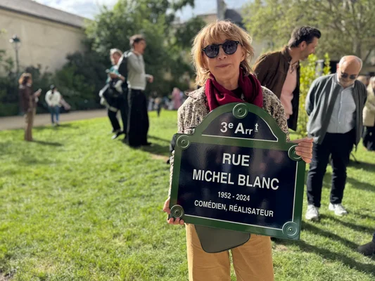 Membre de la troupe du Splendid tenant la plaque de la rue Michel-Blanc lors de l'inauguration dans le Marais.
