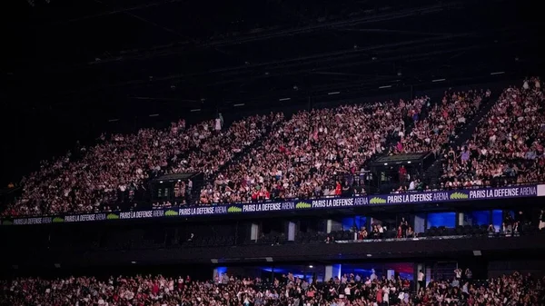 Vue des tribunes complètes du Paris La Défense Arena avec affichage de la marque.