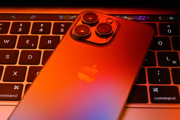 Un iPhone 13 Pro et un MacBook Pro sous un éclairage contrasté.