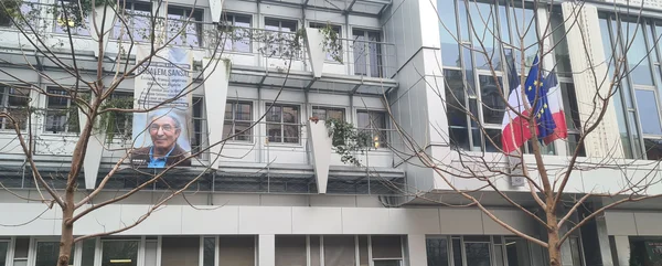 Bâtiment aux Batignolles orné de drapeaux et d'une banderole demandant la libération de Boualem Sansal.