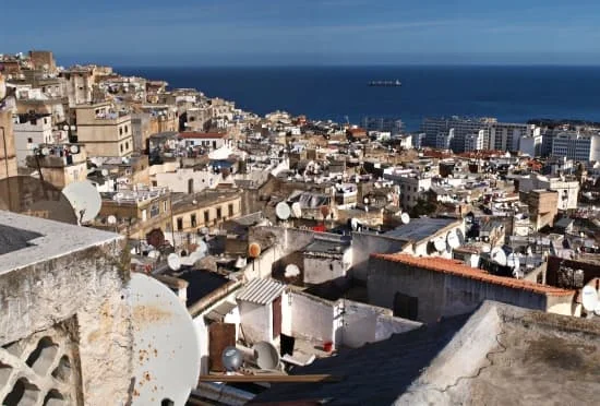 Paysage urbain d'une ville côtière algérienne avec de nombreux bâtiments et une vue sur la mer.