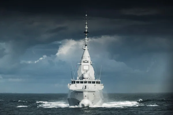 La frégate FDI de Naval Group sur mer agitée sous un ciel orageux, avec sa superstructure anguleuse.