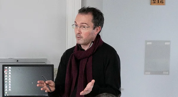 Samuel Paty en train d'enseigner, gestiquant devant un écran d'ordinateur dans sa salle de classe.