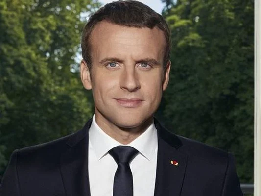 Portrait officiel d'Emmanuel Macron pris dans son bureau devant les jardins.