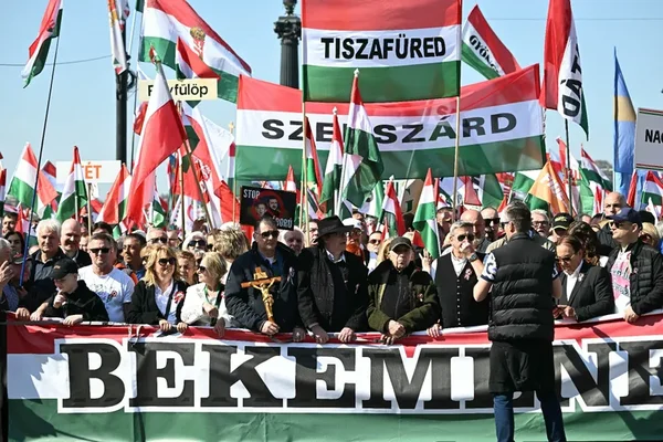 Des partisans défilant avec des drapeaux et des banderoles lors d'un meeting politique en plein air.