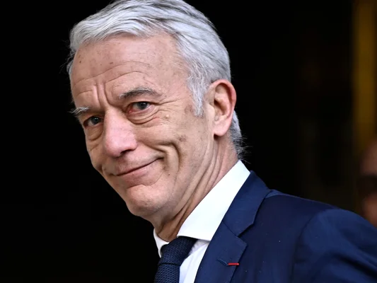 Patrick Martin en costume bleu marine et chemise blanche.