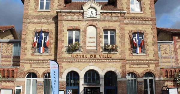 La façade de l'hôtel de ville de Noisiel ornée de drapeaux et de jardinières.