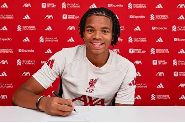 Rio Ngumoha signant son premier contrat professionnel avec Liverpool FC, vêtu du maillot blanc du club.