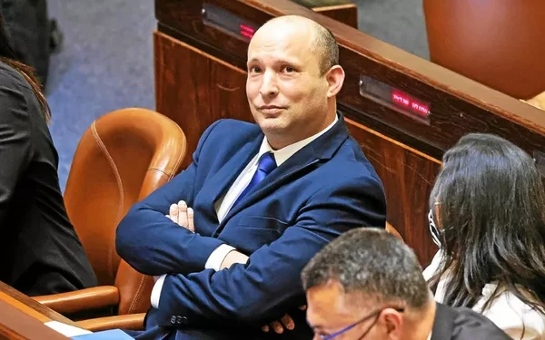 Naftali Bennett assis dans un cadre officiel, entouré de collaborateurs.