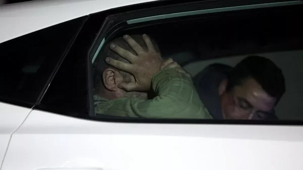 Cédric Prizzon dans un véhicule blanc de nuit, en chemise verte, tenant sa tête entre ses mains.