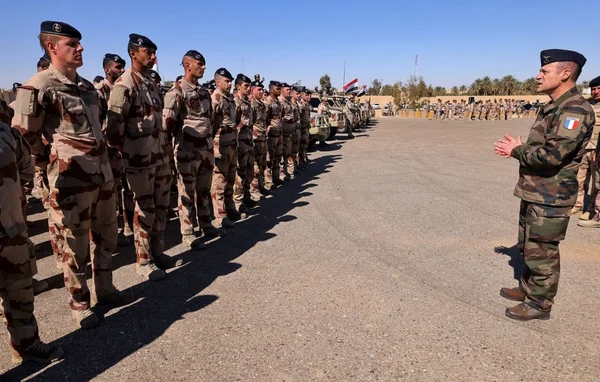 Des militaires en faction à l'entrée d'un bunker de sacs de sable surveillant une tranchée et des collines.