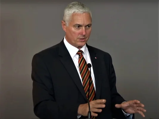 Michel Yakovleff s'exprimant lors d'une conférence de presse derrière un podium.